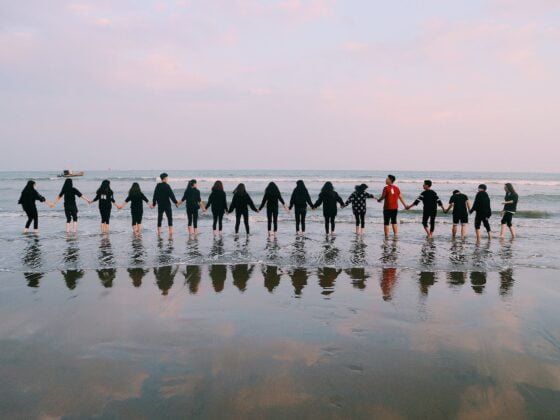 team holding their hands on seashore