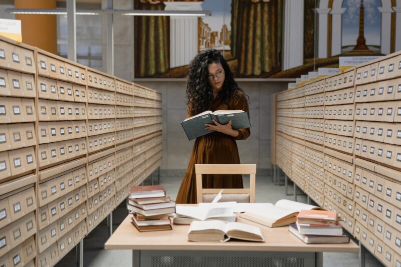 woman reading a book between archive drawers