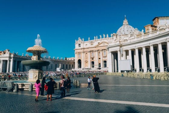 white building and people standing near water fountain at St Peter's basilica in Rome