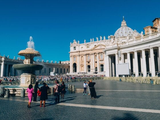 white building and people standing near water fountain at St Peter's basilica in Rome