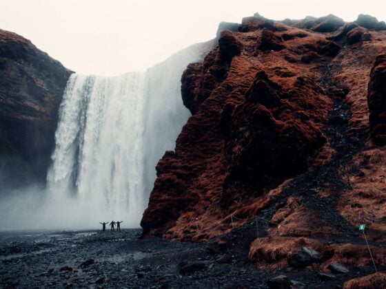 three men standing near waterfalls