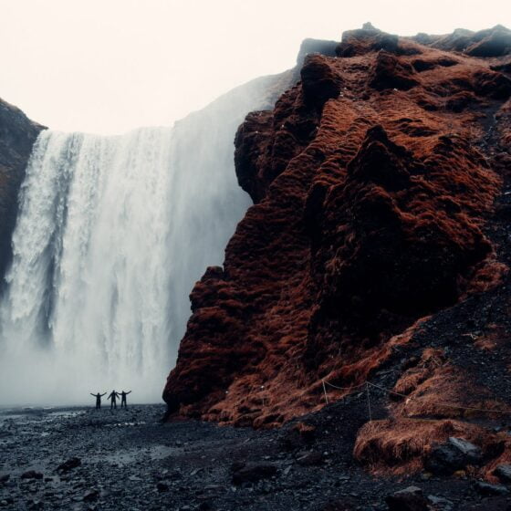 three men standing near waterfalls