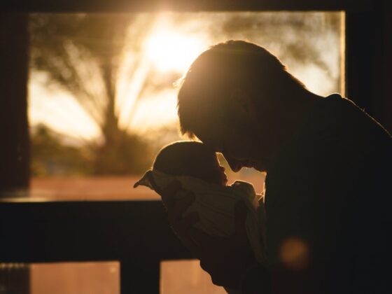 man carrying baby drawing their foreheads