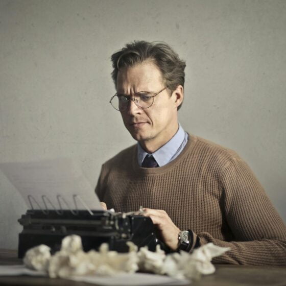 adult frowned male writer working on typewriter at home