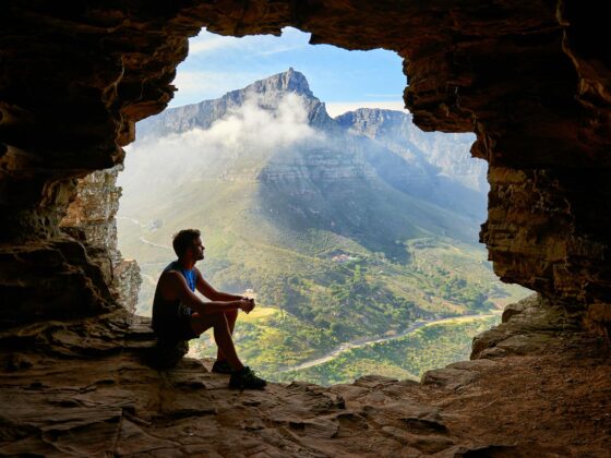 photo of man sitting on a cave