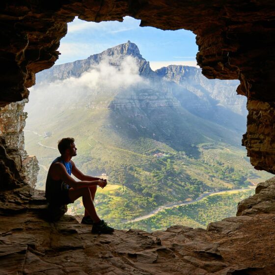 photo of man sitting on a cave