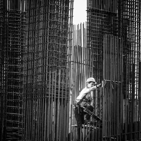 Black and white image of a construction worker climbing steel frameworks in Batumi, Georgia.