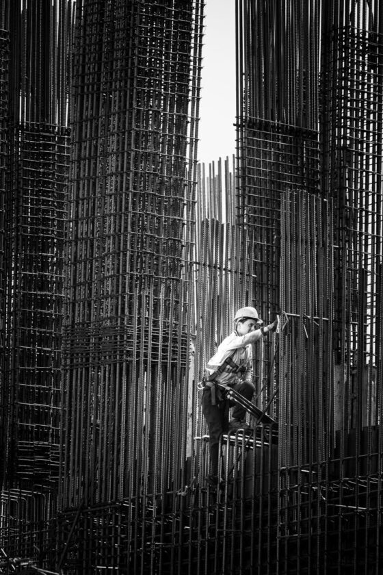 Black and white image of a construction worker climbing steel frameworks in Batumi, Georgia.