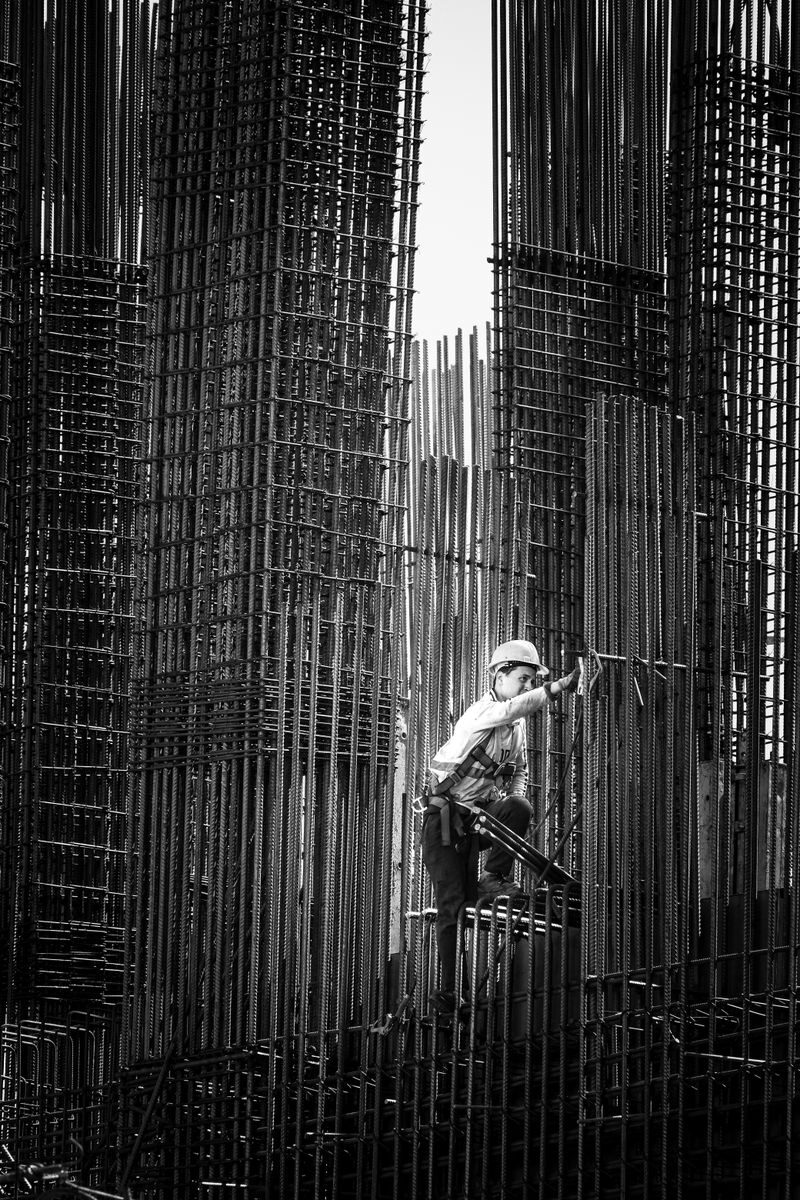 Black and white image of a construction worker climbing steel frameworks in Batumi, Georgia.