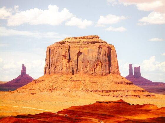 A large red sandstone butte rising above a desert landscape in Monument Valley.