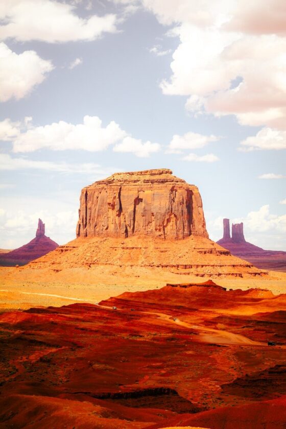 A large red sandstone butte rising above a desert landscape in Monument Valley.